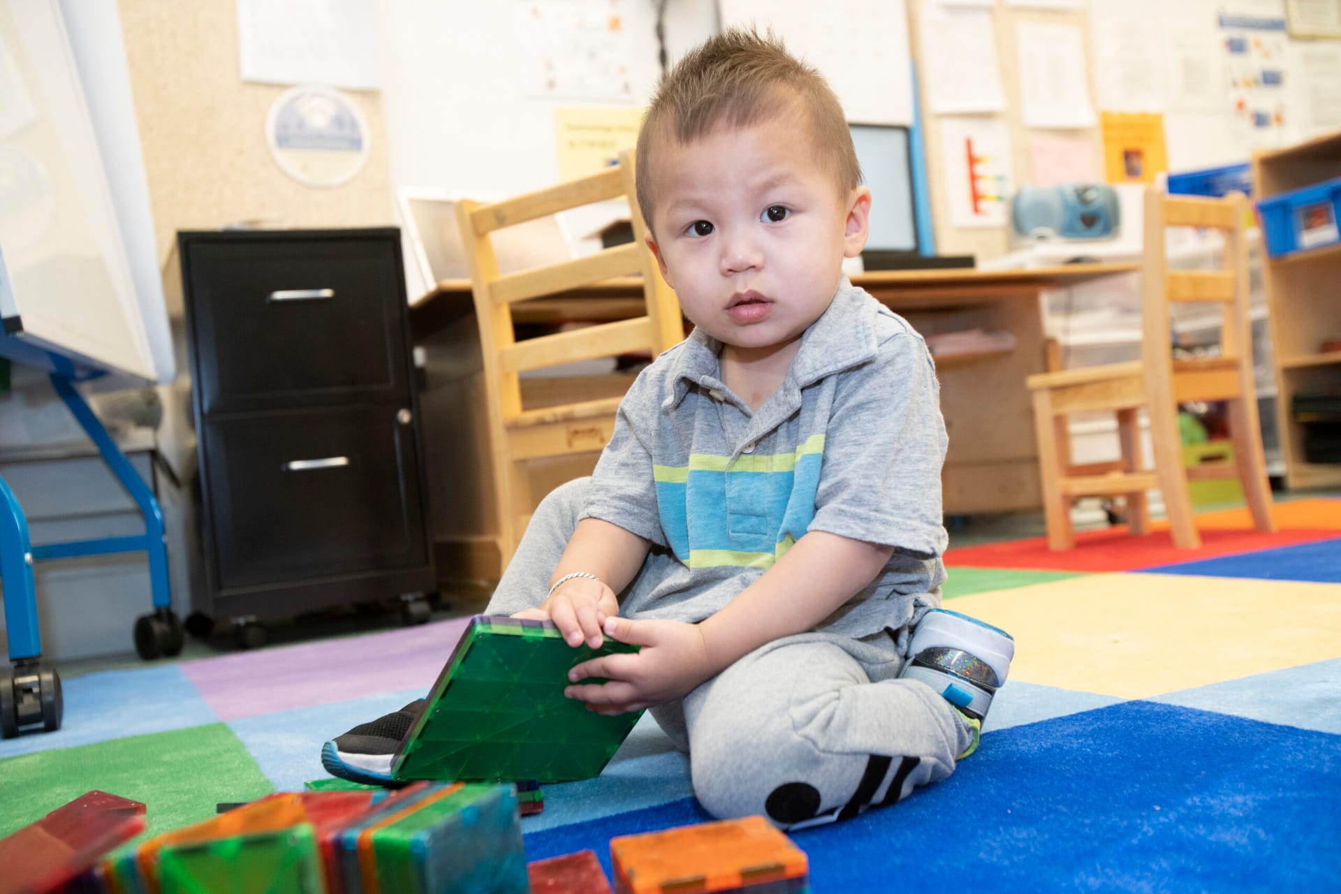 A little boy playing with blocks in a classroom.