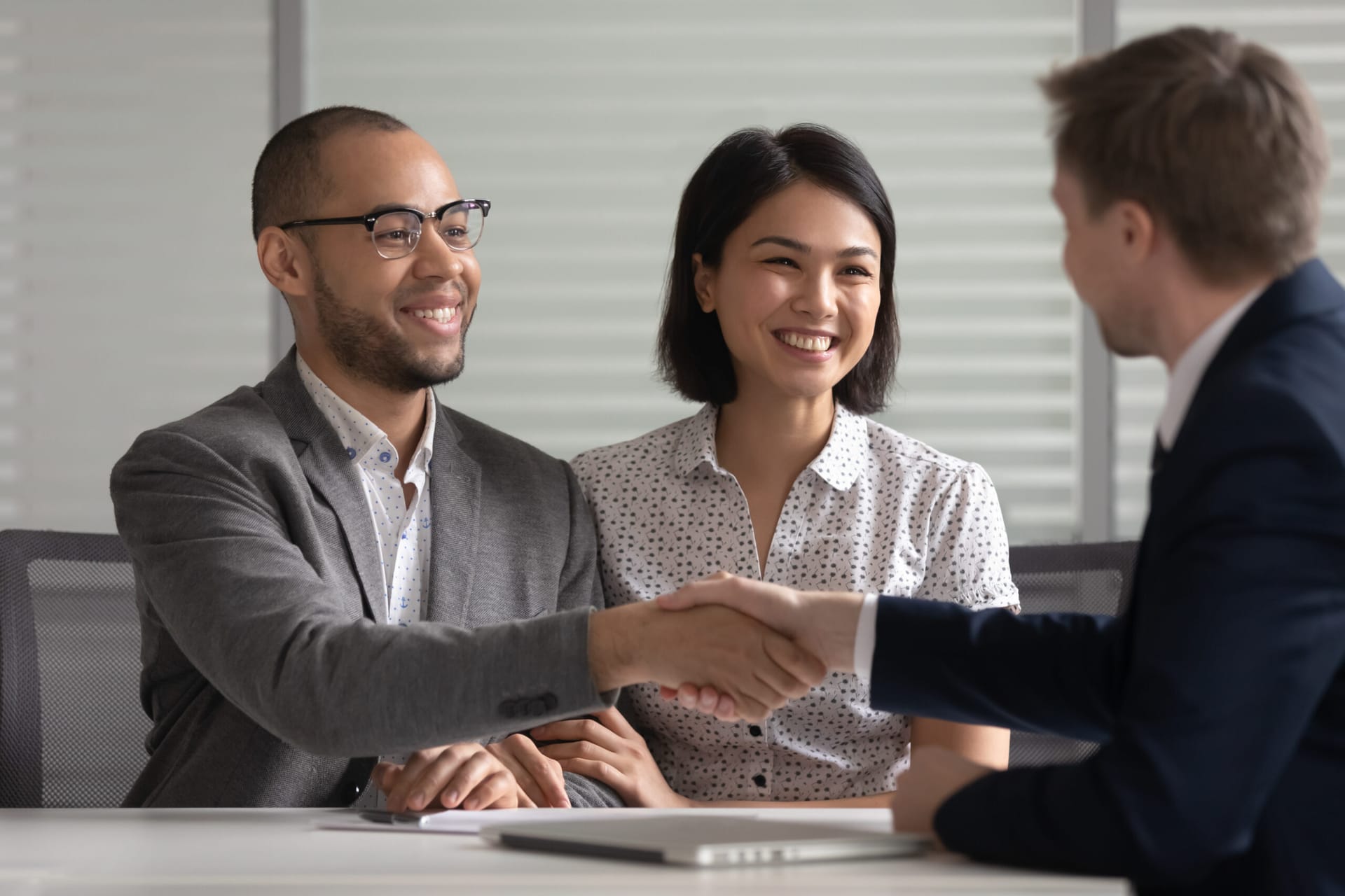 Smiling couple shaking hands with attorney