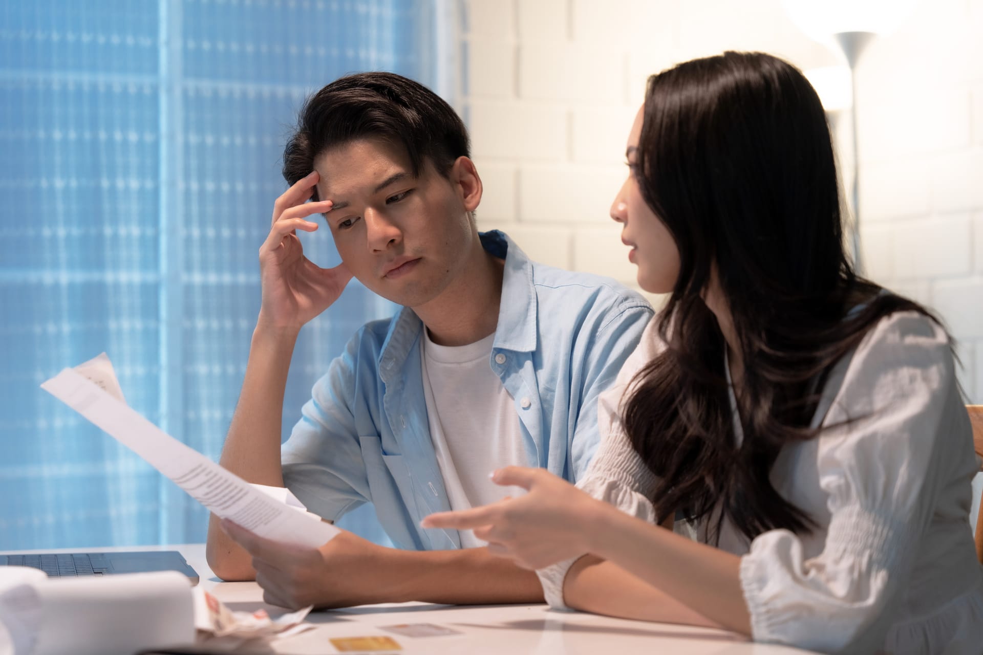 Asian couple looking concerned as they read paperwork