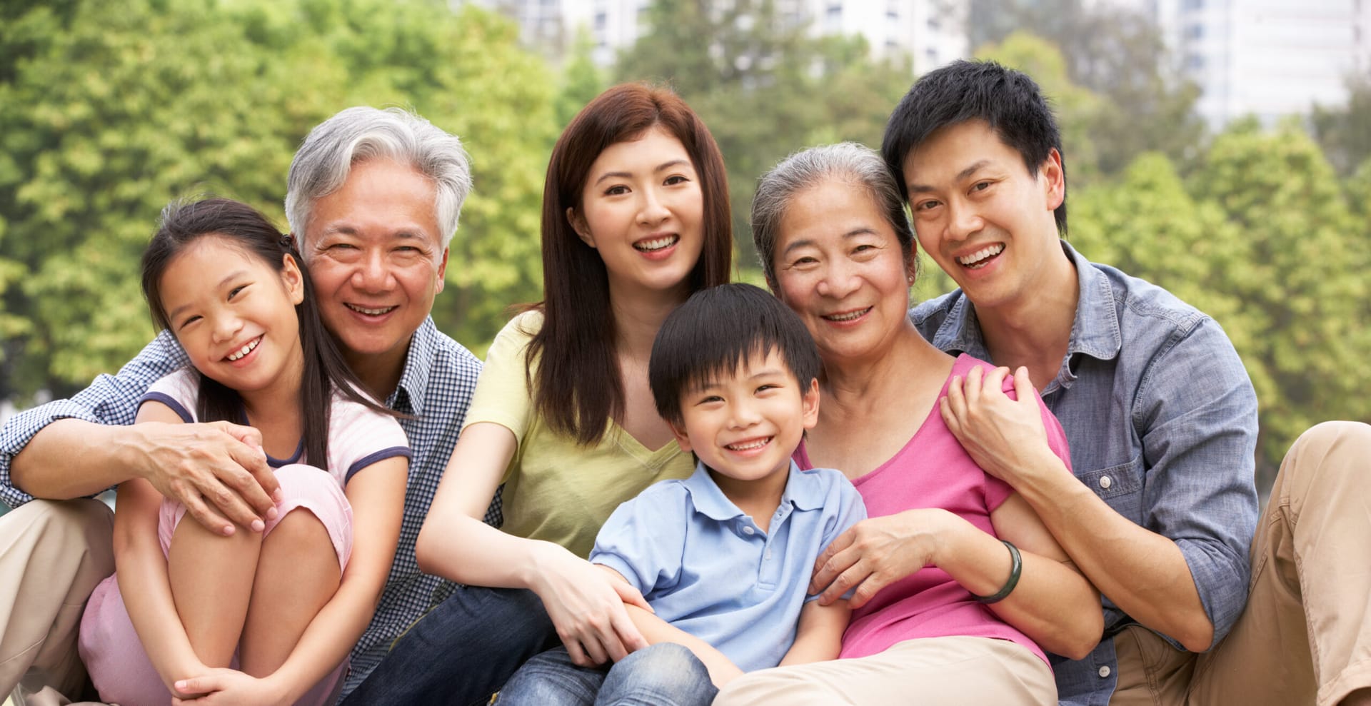 Hugging Asian family seated together on the grass