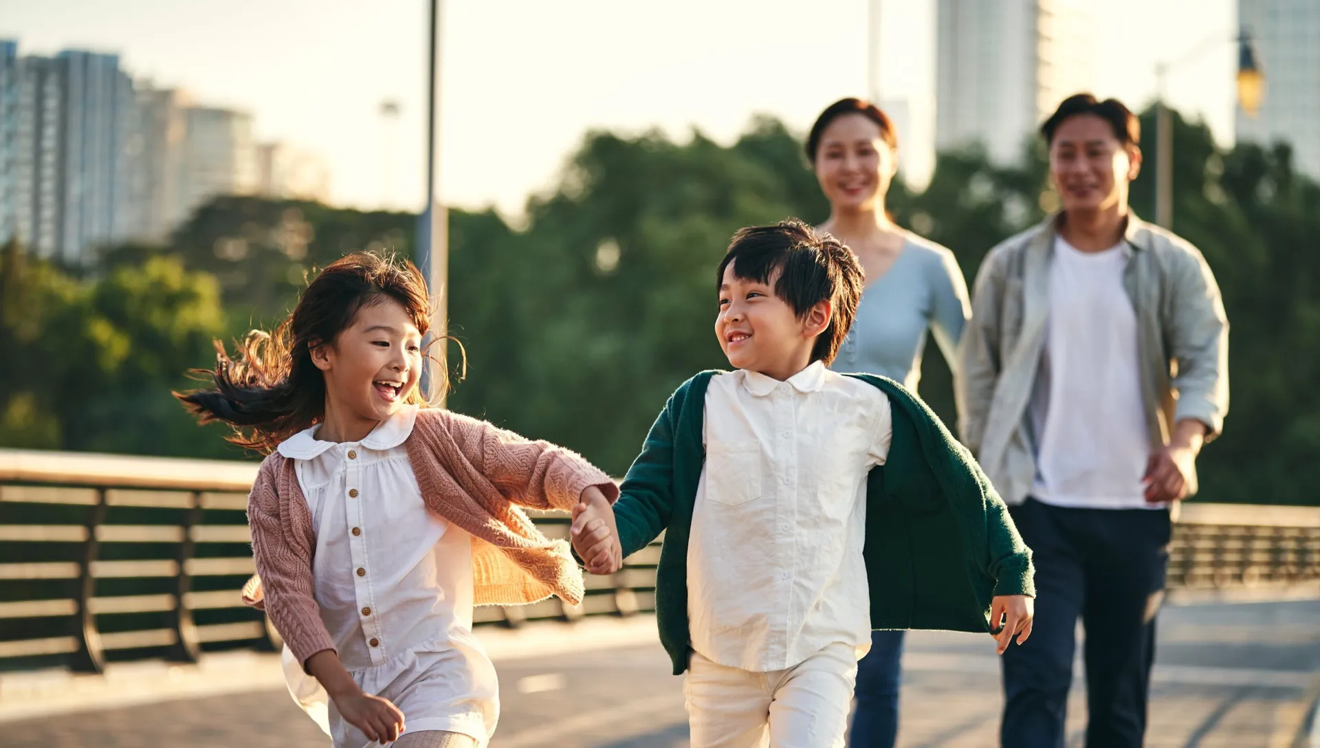 Asian family on a walk through the city, children hand in hand, smiling.